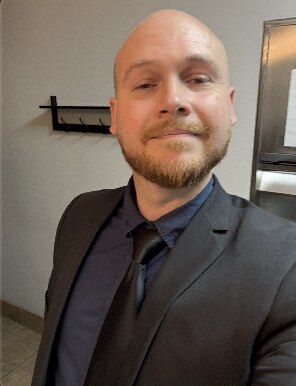 Joey smiling in a dark suit and tie