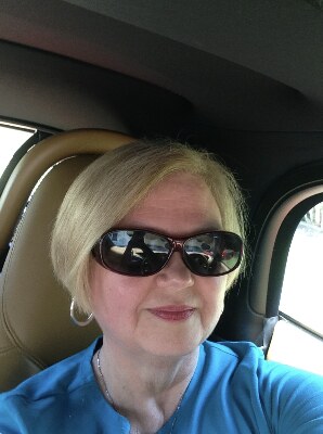 Pam smiling in sunglasses and a blue top